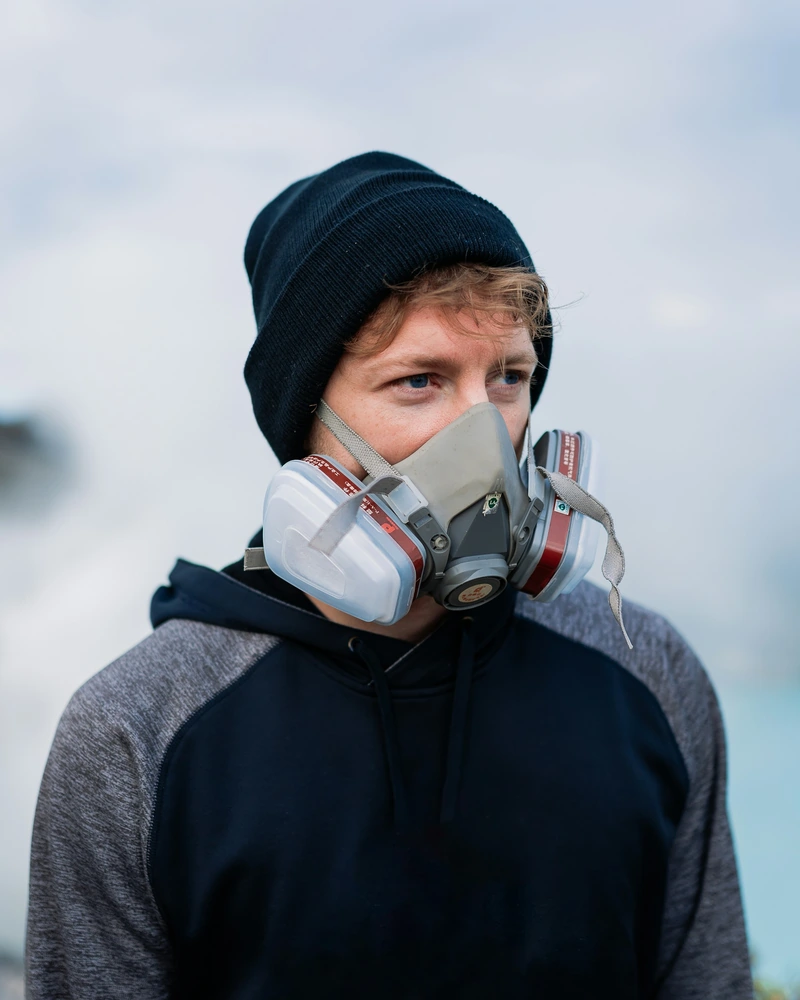 Trekker in a beanie, fleece and gas mask